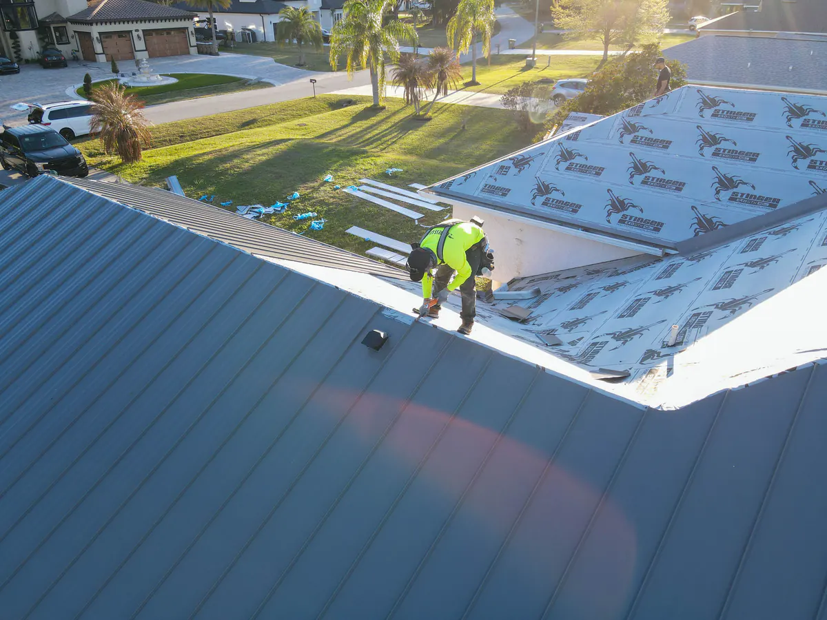 TruTop Roof installer setting grey standing seam panels beside the underlayment on the Kissimmee roof