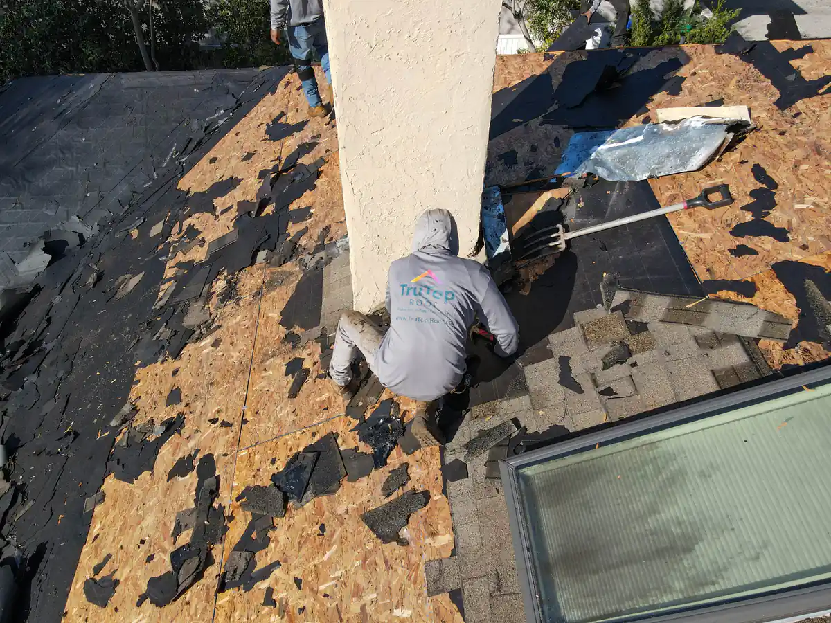 Roofer in a TruTop Roof shirt working beside the chimney and skylight