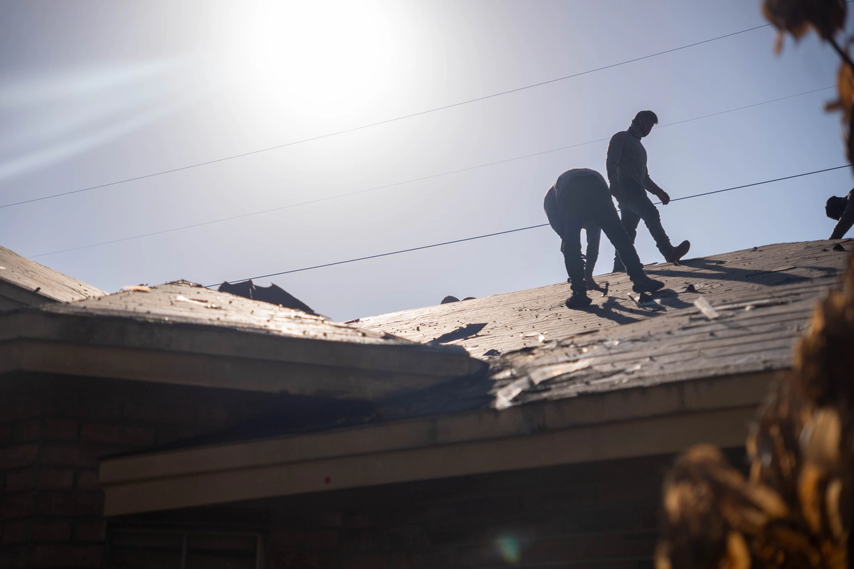 TruTop Roof crew stripping old shingles off the Orlando home with the sun behind them